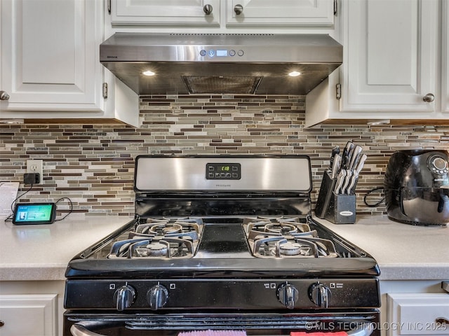 124 Canterbury Ct, Bartlesville, OK 74006 - kitchen view of range with gas cooktop, under cabinet range hood, light countertops, white cabinets, and backsplash