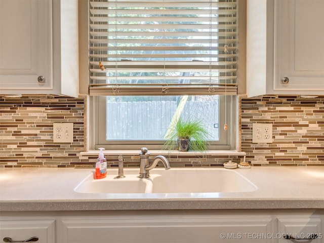 124 Canterbury Ct, Bartlesville, OK 74006 - kitchen featuring a sink, tasteful backsplash, light countertops, white cabinets, and plenty of natural light