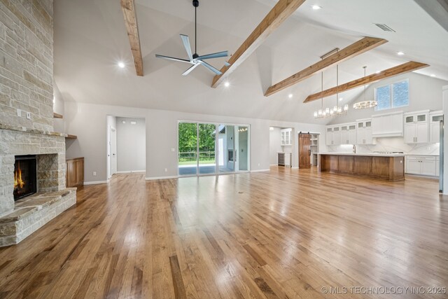 682 W 113th Ct S, Jenks, OK 74037 - unfurnished living room featuring high vaulted ceiling, a stone fireplace, ceiling fan, beamed ceiling, and light wood-style flooring