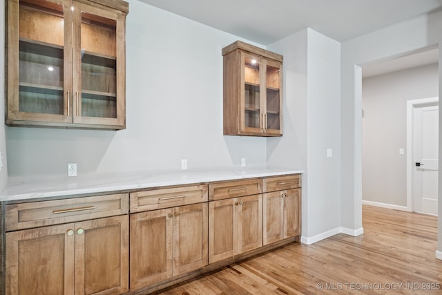 682 W 113th Ct S, Jenks, OK 74037 - kitchen with light wood-style flooring, light countertops, glass insert cabinets, and brown cabinets
