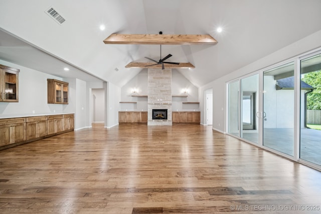 682 W 113th Ct S, Jenks, OK 74037 - unfurnished living room with beamed ceiling, a ceiling fan, wood finished floors, high vaulted ceiling, and a fireplace