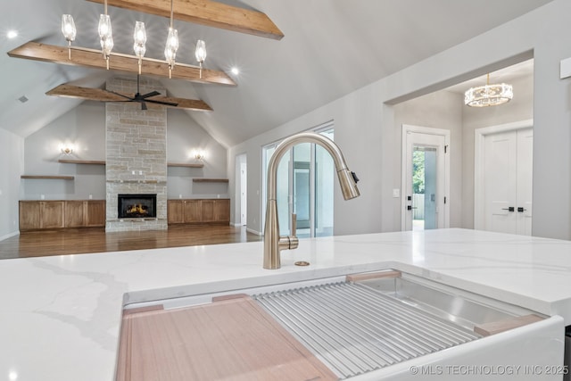 682 W 113th Ct S, Jenks, OK 74037 - kitchen featuring beam ceiling, light stone countertops, a ceiling fan, open floor plan, and a stone fireplace