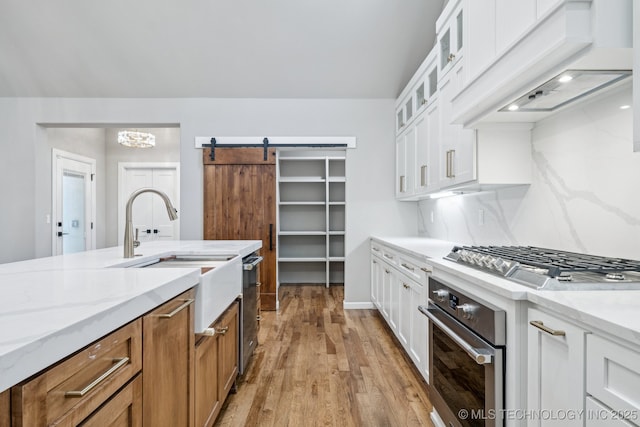 682 W 113th Ct S, Jenks, OK 74037 - kitchen with stainless steel appliances, custom range hood, light wood-style flooring, light stone countertops, and white cabinets