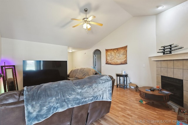 14507 E 110th Pl, Owasso, OK 74055 - living room featuring vaulted ceiling, ceiling fan, a fireplace, light wood-style floors, and arched walkways