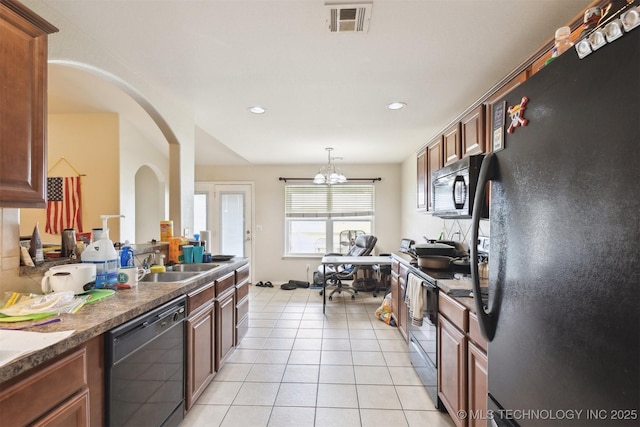 14507 E 110th Pl, Owasso, OK 74055 - kitchen with black appliances, a sink, arched walkways, dark countertops, and light tile patterned floors