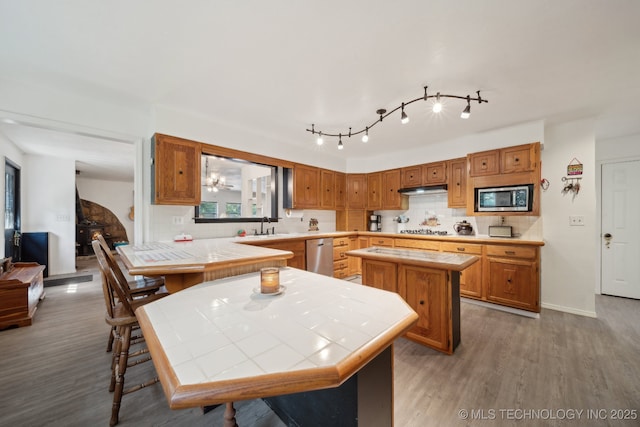 239 Seneca Dr, Sand Springs, OK 74063 - kitchen with appliances with stainless steel finishes, a sink, tile counters, decorative backsplash, and wood finished floors