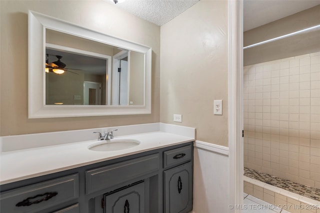 bathroom featuring tiled shower, vanity, a textured ceiling, and a ceiling fan