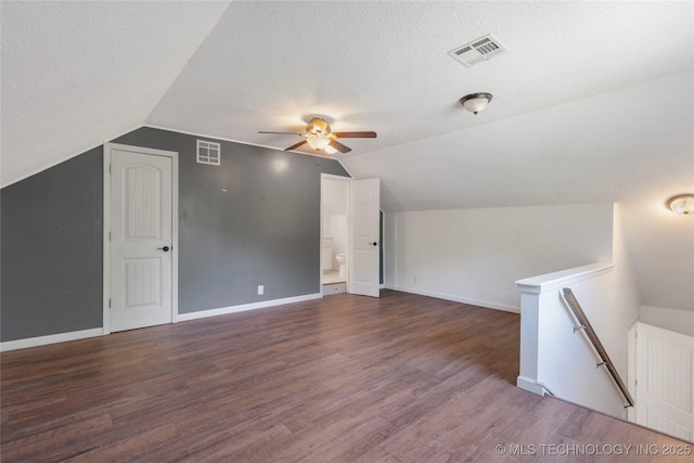 bonus room featuring vaulted ceiling, a ceiling fan, wood finished floors, baseboards, and a textured ceiling