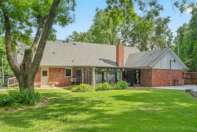 back of house featuring brick siding, a sunroom, a chimney, and roof with shingles