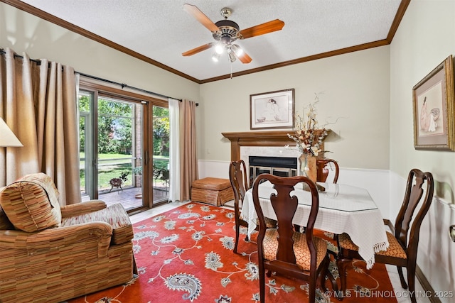 3805 E 64th Pl, Tulsa, OK 74136 - dining space with a textured ceiling, ceiling fan, ornamental molding, a glass covered fireplace, and a wainscoted wall