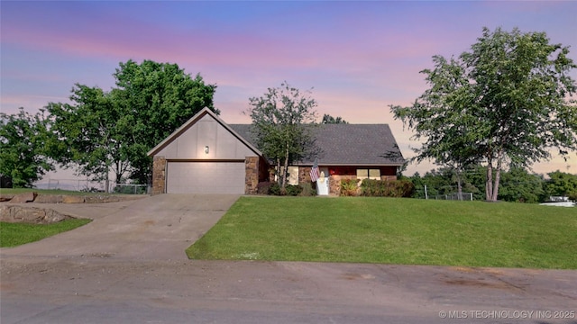 view of front of property featuring driveway, an attached garage, a yard, and stone siding