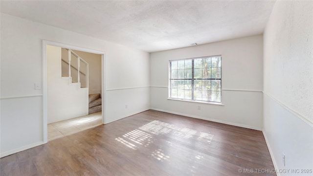 unfurnished room with wood finished floors and stairway