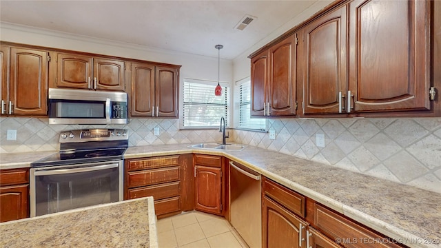 kitchen featuring stainless steel appliances, a sink, light countertops, decorative light fixtures, and ornamental molding