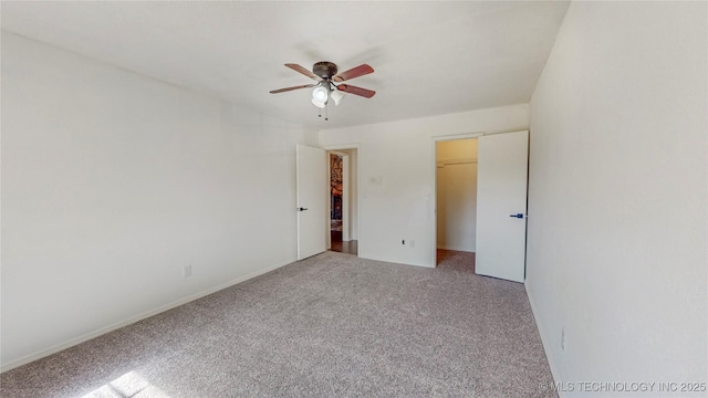 unfurnished bedroom featuring carpet floors, a spacious closet, and ceiling fan