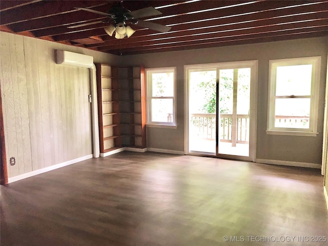 509 N Michigan Ave, Cushing, OK 74023 - unfurnished room with a wall mounted air conditioner, ceiling fan, wood walls, wood finished floors, and baseboards