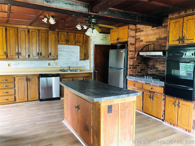 509 N Michigan Ave, Cushing, OK 74023 - kitchen featuring appliances with stainless steel finishes, a warming drawer, brown cabinetry, light wood finished floors, and beam ceiling