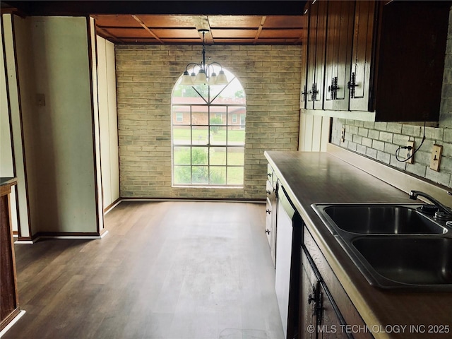 509 N Michigan Ave, Cushing, OK 74023 - kitchen with brick wall, a sink, dark countertops, pendant lighting, and a chandelier