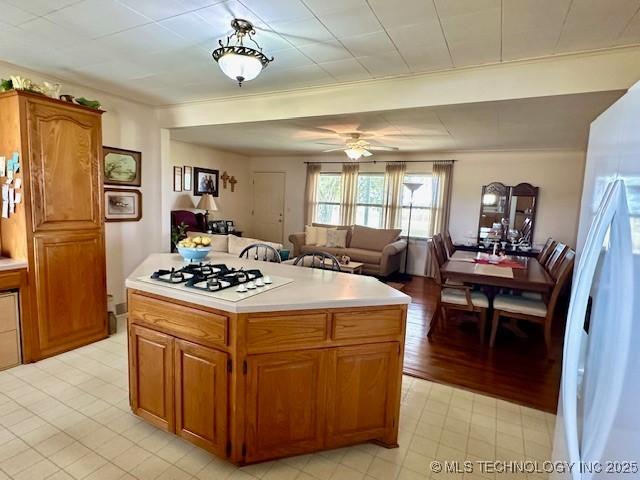 27414 S 4440th Rd, Vinita, OK 74301 - kitchen with white appliances, light countertops, brown cabinets, a center island, and crown molding
