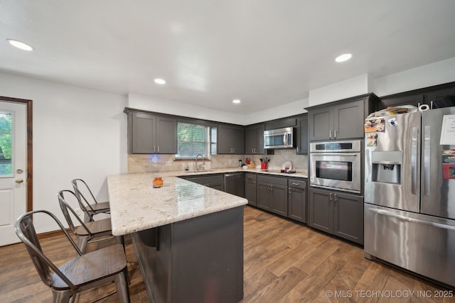 215 Rodman Cir, Muskogee, OK 74403 - kitchen with appliances with stainless steel finishes, a sink, a peninsula, a breakfast bar, and tasteful backsplash