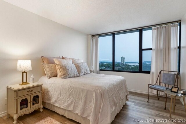 410 W 7th St Unit 1722, Tulsa, OK 74119 - bedroom featuring baseboards and light wood-style floors