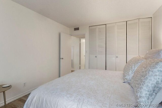410 W 7th St Unit 1722, Tulsa, OK 74119 - bedroom featuring wood finished floors, a closet, and a textured ceiling