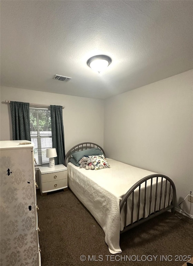 205 Ury, Caddo, OK 74729 - bedroom featuring dark carpet and a textured ceiling
