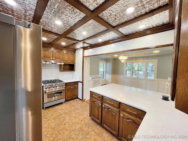 525 W Downing St, Tahlequah, OK 74464 - kitchen with stainless steel appliances, under cabinet range hood, wainscoting, light stone counters, and light tile patterned floors