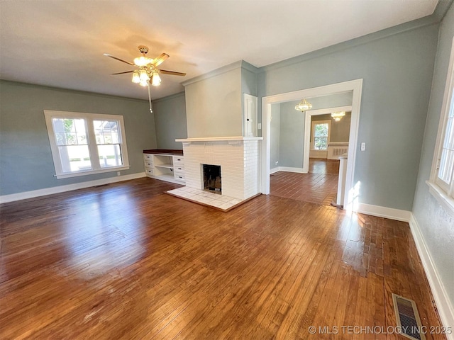 525 W Downing St, Tahlequah, OK 74464 - unfurnished living room featuring wood-type flooring, ceiling fan, a brick fireplace, baseboards, and crown molding