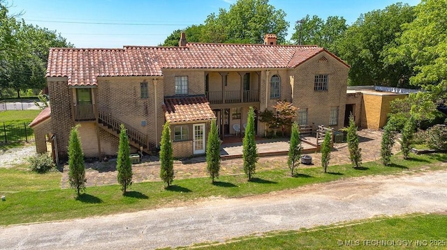 mediterranean / spanish home with a tiled roof, a chimney, and stucco siding