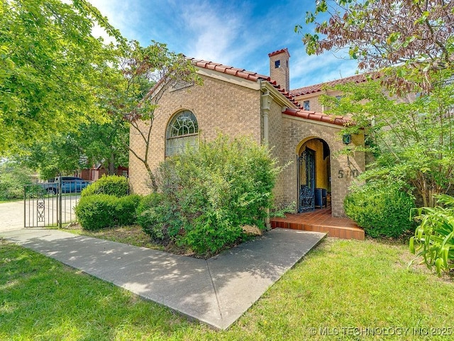 mediterranean / spanish-style house with a tile roof, a chimney, and stucco siding