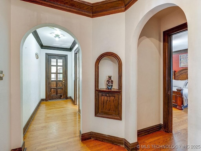 hall featuring ornamental molding, light wood-style floors, and baseboards