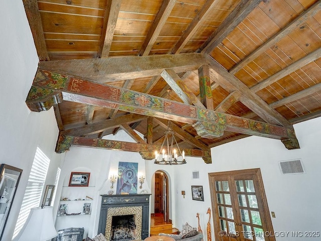 living room with arched walkways, wood ceiling, beamed ceiling, a tiled fireplace, and a chandelier