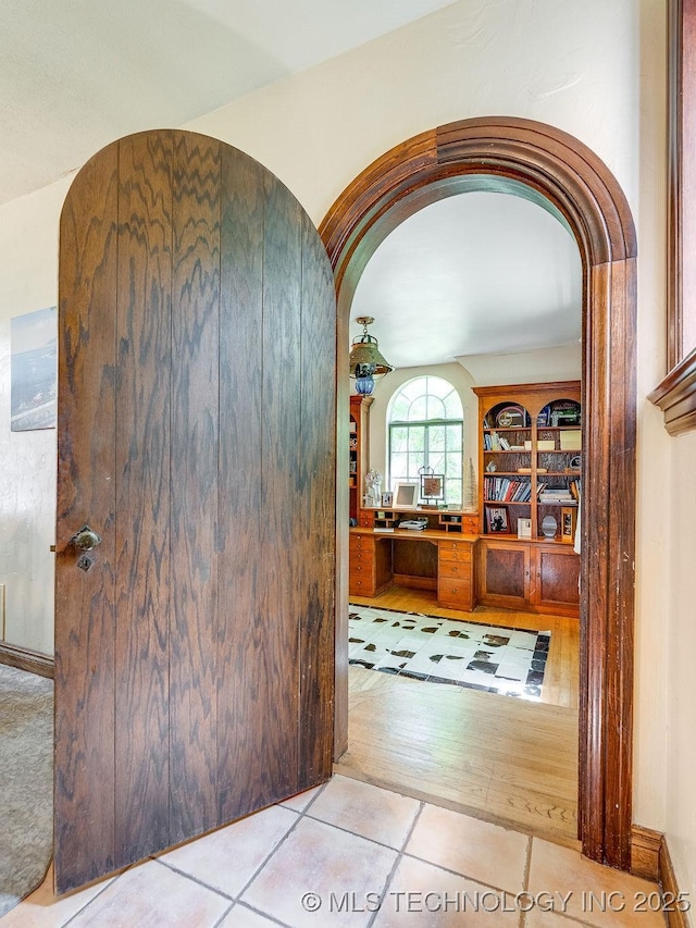 hall with arched walkways and tile patterned flooring