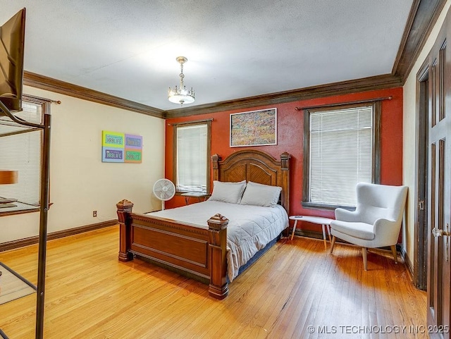 bedroom with ornamental molding, light wood-type flooring, baseboards, and a chandelier