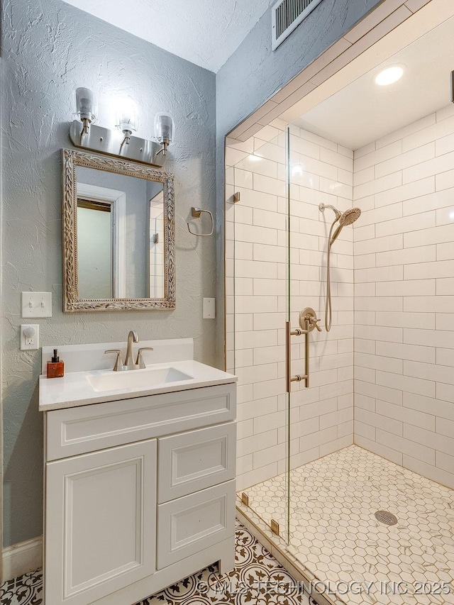full bath with a shower stall, a textured wall, vanity, and tile patterned flooring