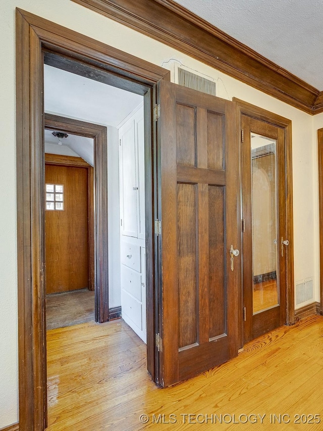 hall with light wood finished floors, crown molding, and baseboards