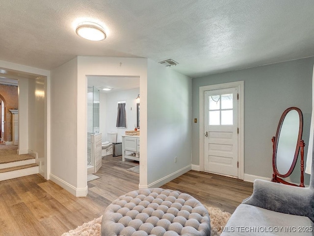 foyer with light wood-style floors, baseboards, and a textured ceiling