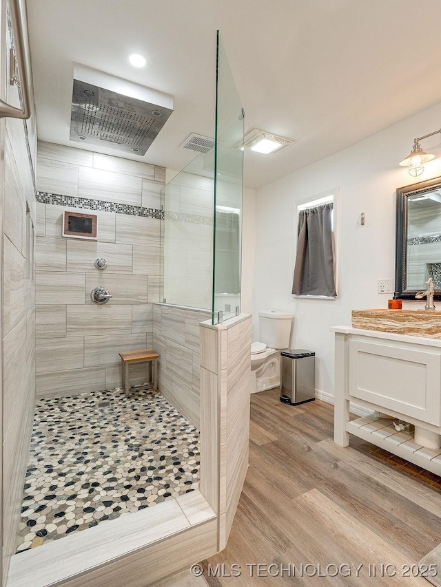 bathroom with a walk in shower, vanity, wood finished floors, baseboards, and recessed lighting