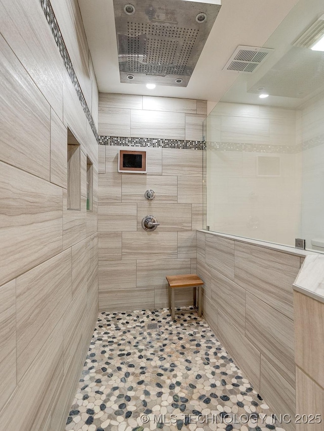 bathroom featuring tile walls and a tile shower