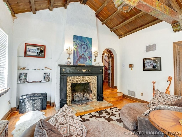 living room featuring wooden ceiling, arched walkways, wood finished floors, healthy amount of natural light, and a tiled fireplace