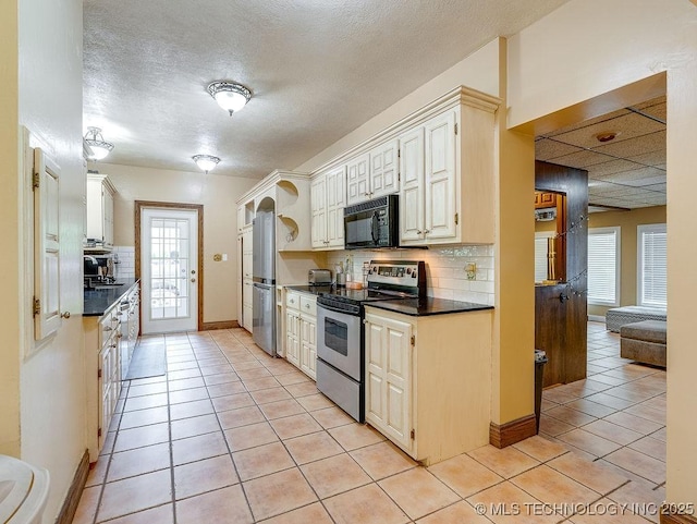 kitchen featuring stainless steel appliances, dark countertops, decorative backsplash, light tile patterned floors, and a textured ceiling
