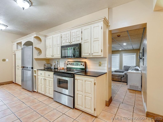 kitchen with stainless steel appliances, dark countertops, light tile patterned floors, decorative backsplash, and a textured ceiling