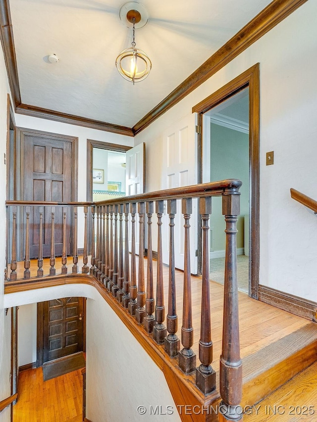stairs featuring wood finished floors, ornamental molding, and baseboards