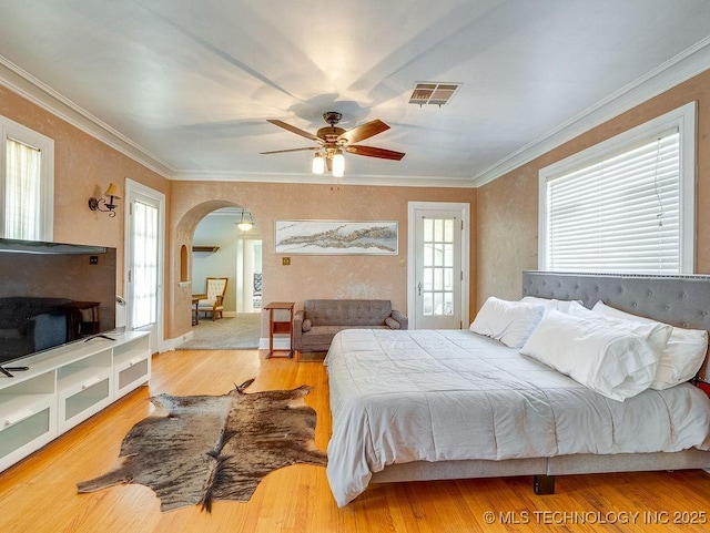 bedroom with arched walkways, wood finished floors, ornamental molding, and ceiling fan