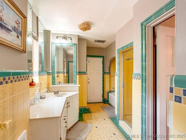 bathroom featuring a shower stall, tile walls, and vanity