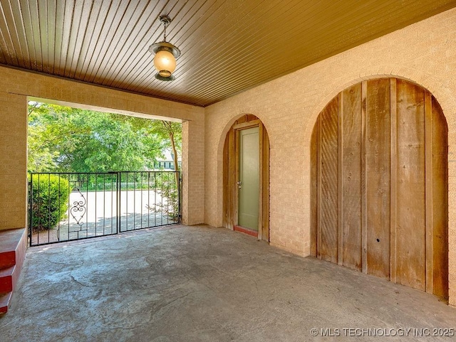 empty room featuring wood ceiling, arched walkways, and concrete floors