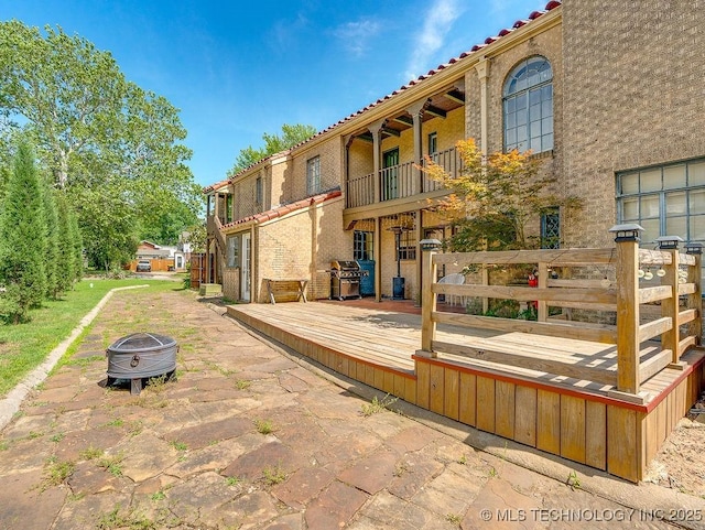 rear view of property with a fire pit, a balcony, a deck, and a tiled roof