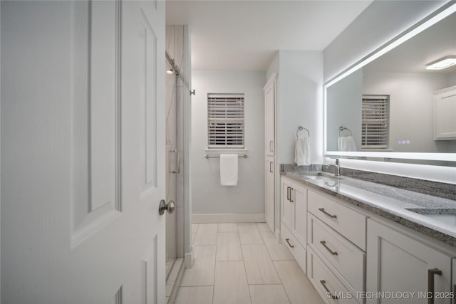 bathroom featuring baseboards, double vanity, and a shower