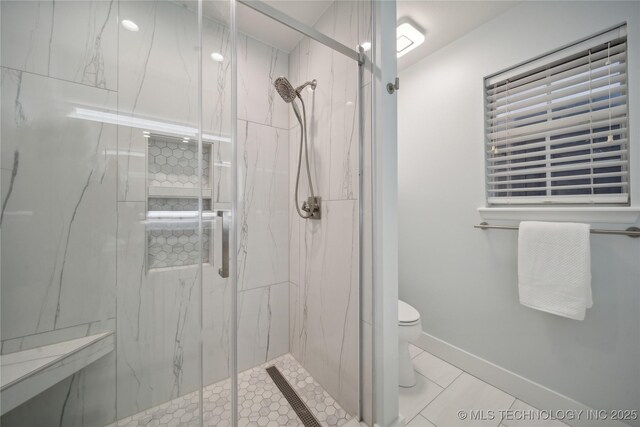 bathroom with a marble finish shower, toilet, tile patterned floors, and baseboards