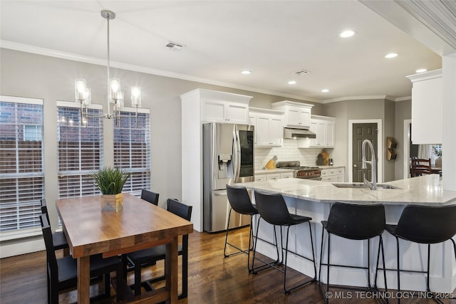 kitchen with appliances with stainless steel finishes, a sink, crown molding, tasteful backsplash, and white cabinets